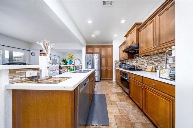 kitchen with stainless steel appliances, an island with sink, sink, and tasteful backsplash