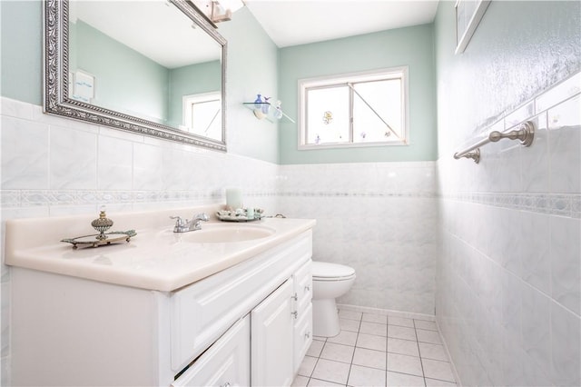 bathroom featuring wainscoting, toilet, tile patterned flooring, vanity, and tile walls