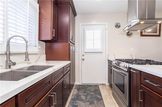 kitchen with light tile patterned flooring, sink, island exhaust hood, light stone counters, and stainless steel range with gas stovetop