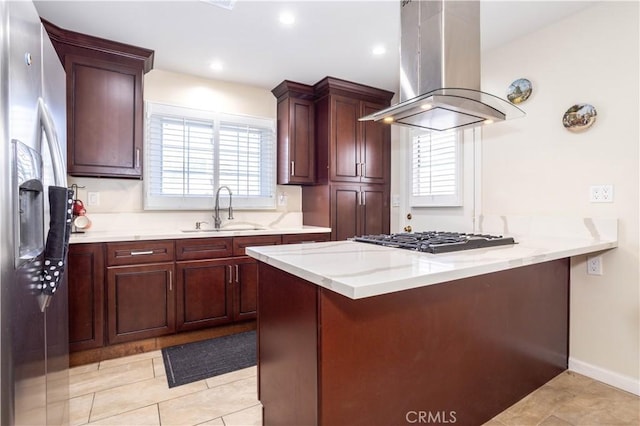 kitchen featuring a peninsula, a sink, appliances with stainless steel finishes, light stone countertops, and island exhaust hood