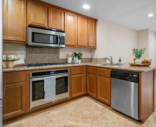 kitchen with sink, appliances with stainless steel finishes, light stone counters, decorative backsplash, and kitchen peninsula