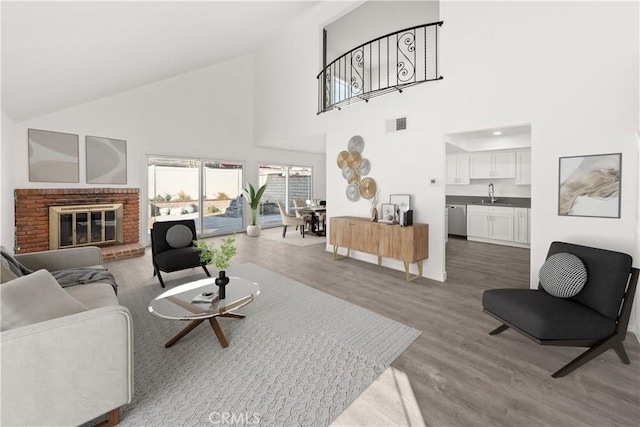 living room featuring lofted ceiling, sink, hardwood / wood-style flooring, and a fireplace