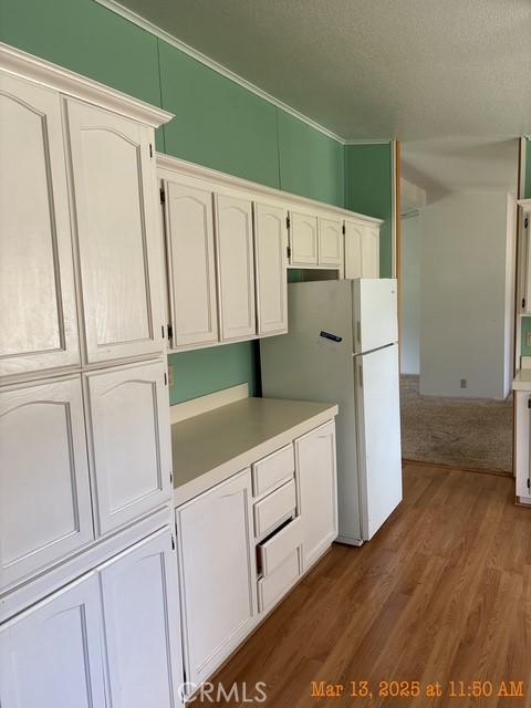 1845 Spring Valley Rd, Clearlake Oaks, CA 95423 - kitchen with freestanding refrigerator, dark wood finished floors, white cabinets, and light countertops