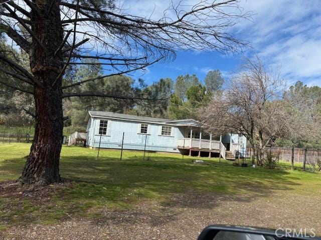 manufactured / mobile home featuring a wooden deck, a front lawn, and fence