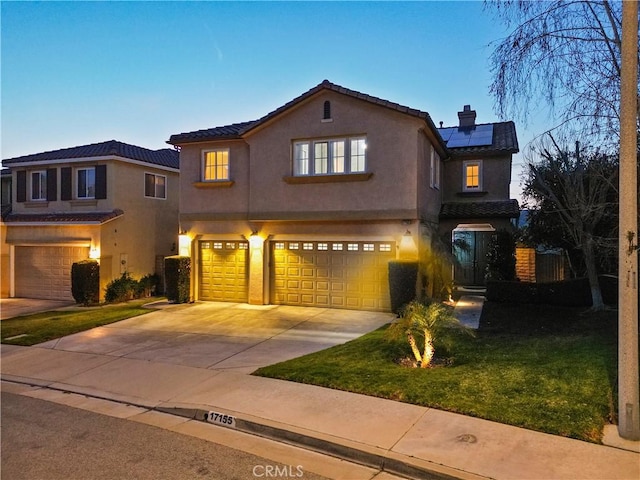 view of front of house with a garage, solar panels, and a lawn