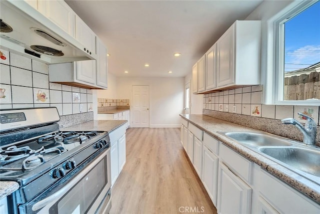 kitchen with sink, white cabinetry, backsplash, light hardwood / wood-style floors, and gas range