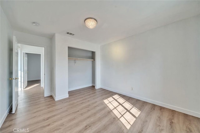 unfurnished bedroom with light wood-type flooring and a closet