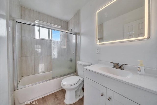 full bathroom featuring vanity, wood-type flooring, bath / shower combo with glass door, and toilet