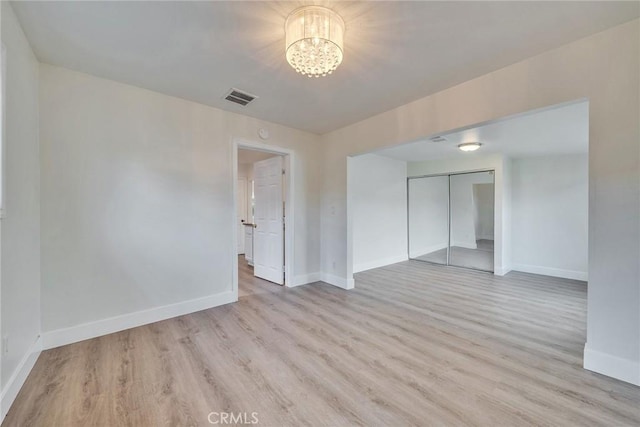 spare room with an inviting chandelier and light hardwood / wood-style floors