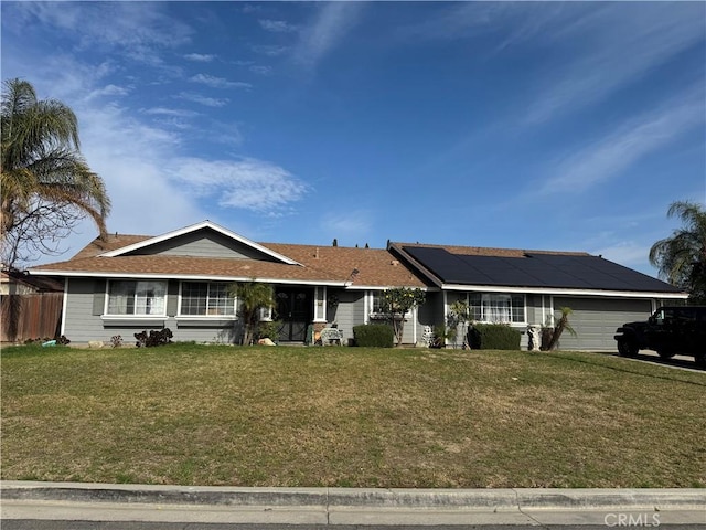 view of front facade featuring a garage, a front lawn, and solar panels