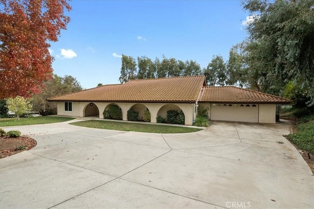 mediterranean / spanish house featuring a garage, driveway, and a tiled roof