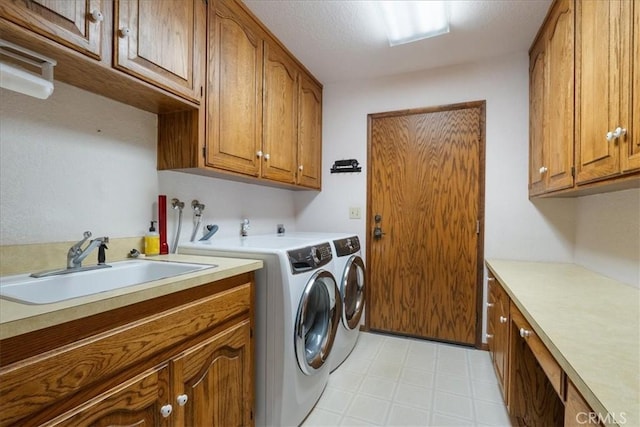 clothes washing area with a sink, cabinet space, light floors, and washer and dryer