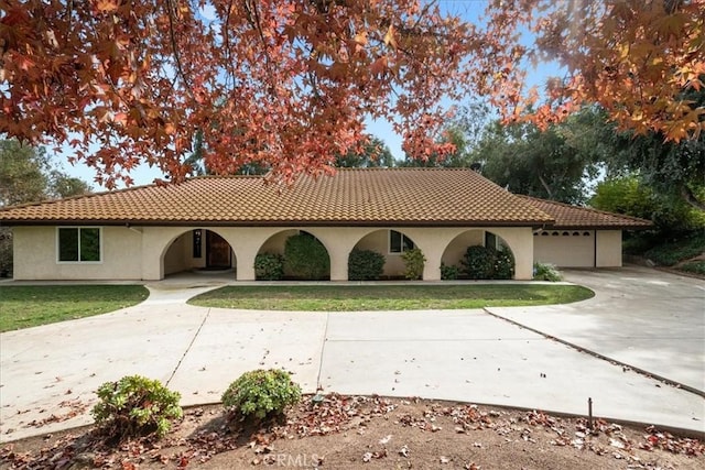 view of front of house featuring concrete driveway, a tiled roof, a front lawn, and stucco siding