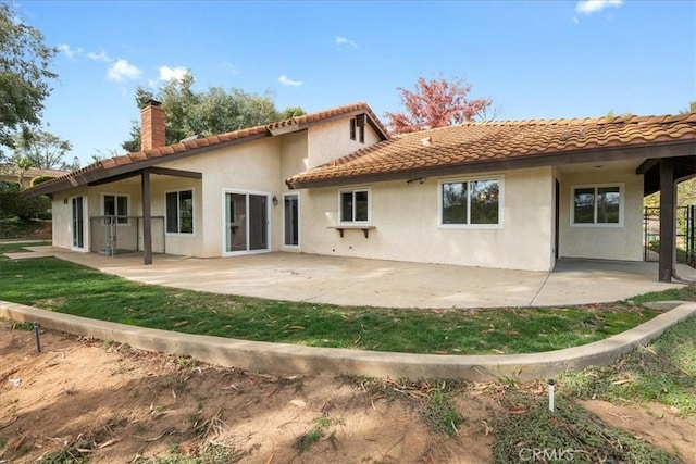 rear view of property with a patio, a chimney, and stucco siding