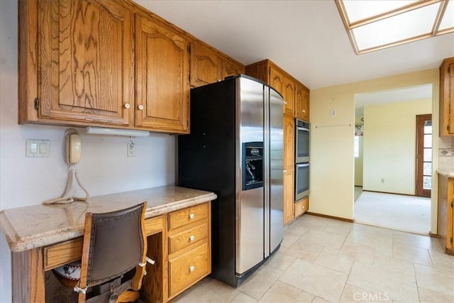 kitchen with brown cabinetry, baseboards, and stainless steel appliances