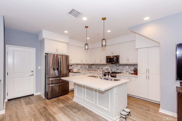 kitchen with sink, white cabinetry, decorative light fixtures, a center island with sink, and stainless steel appliances