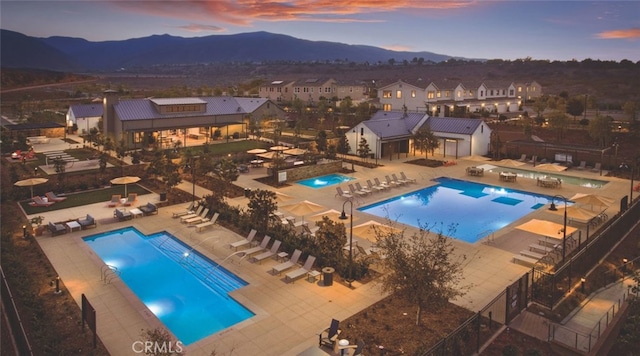 pool at dusk featuring a mountain view and a patio area