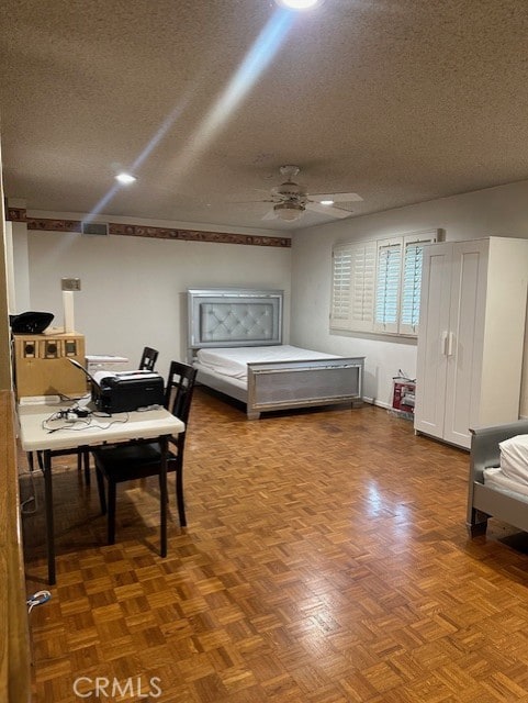 bedroom with parquet floors, a textured ceiling, and ceiling fan