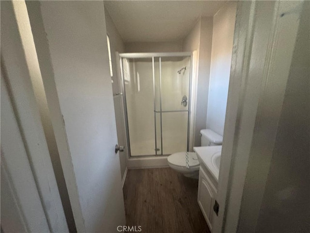 bathroom featuring an enclosed shower, vanity, wood-type flooring, and toilet