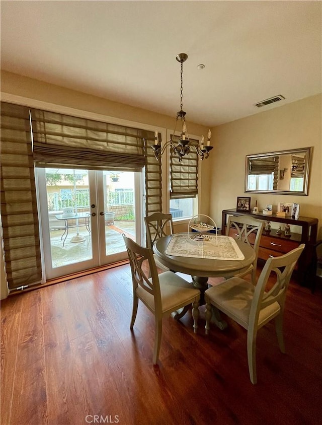 dining room featuring hardwood / wood-style flooring, an inviting chandelier, and french doors