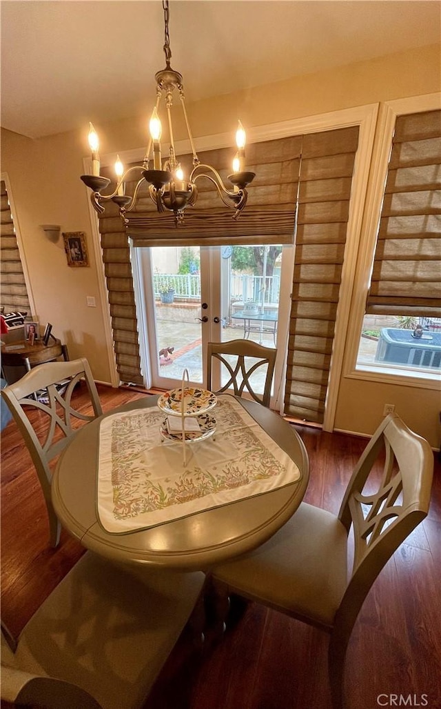 dining space featuring a healthy amount of sunlight, dark hardwood / wood-style floors, a chandelier, and french doors