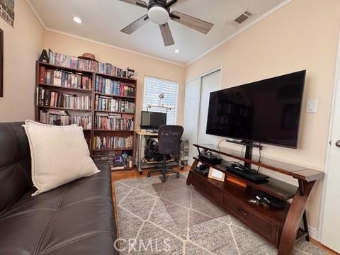 living room featuring crown molding and ceiling fan