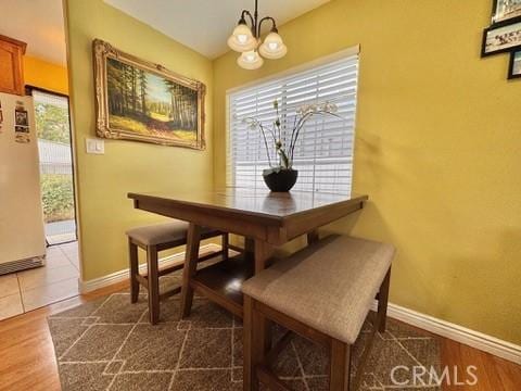 dining space featuring dark wood-type flooring and an inviting chandelier