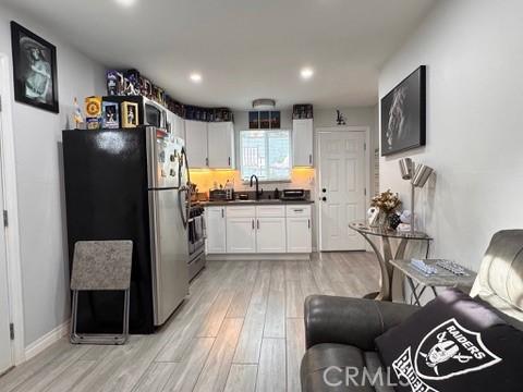 kitchen featuring sink, stainless steel fridge, white cabinets, range, and light hardwood / wood-style flooring