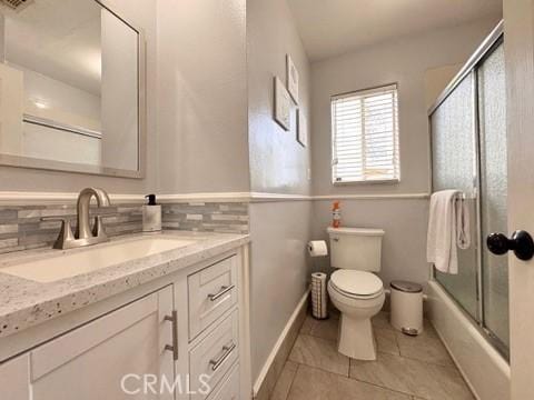 full bathroom with toilet, bath / shower combo with glass door, vanity, tile patterned flooring, and decorative backsplash