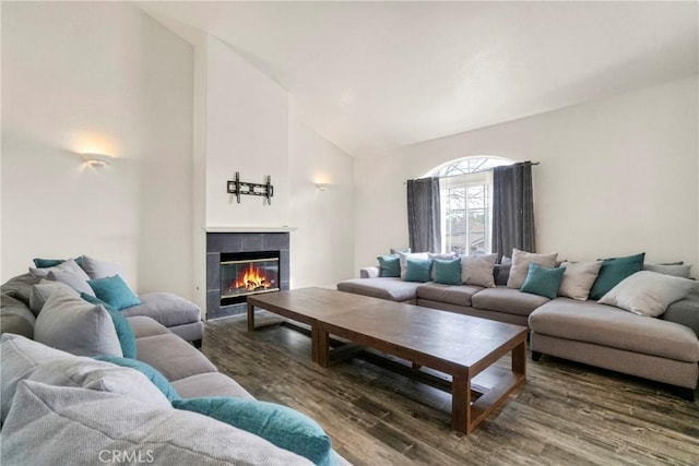 living room featuring a tile fireplace, dark wood-type flooring, and high vaulted ceiling