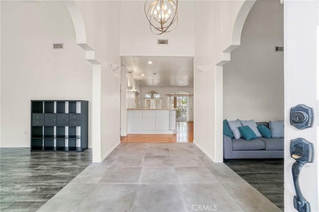 entryway featuring a towering ceiling, wood-type flooring, and a chandelier