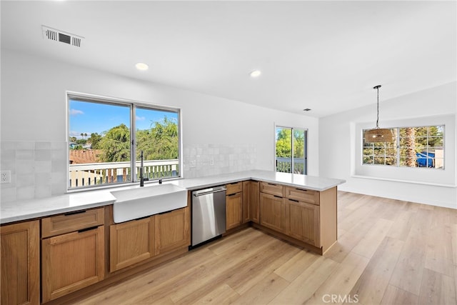 kitchen featuring sink, backsplash, stainless steel dishwasher, kitchen peninsula, and light hardwood / wood-style flooring