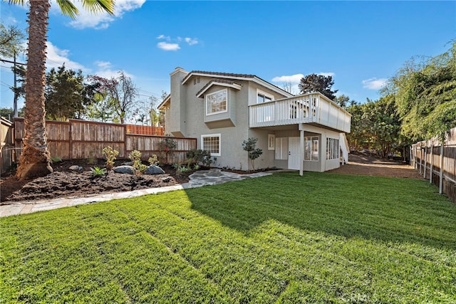 rear view of house featuring a wooden deck and a lawn