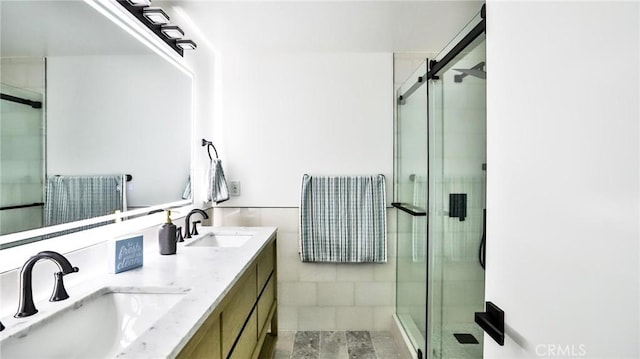 bathroom featuring vanity, a shower with door, and tile walls