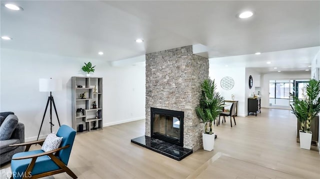 living room featuring a stone fireplace and light hardwood / wood-style floors