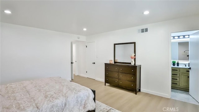 bedroom with ensuite bath and light hardwood / wood-style floors