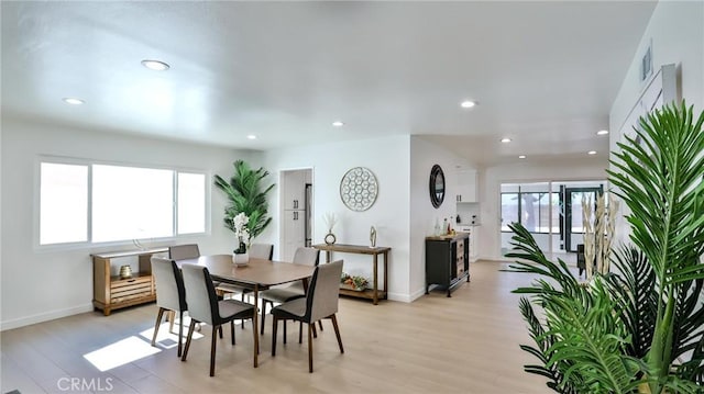 dining space with light hardwood / wood-style floors and a healthy amount of sunlight