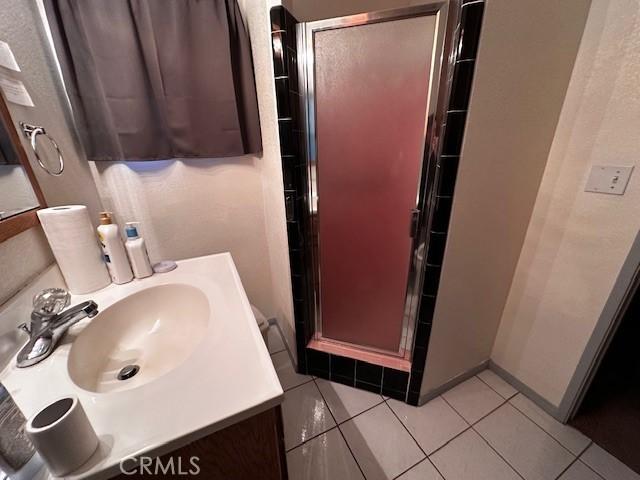 bathroom with tile patterned flooring, vanity, and an enclosed shower