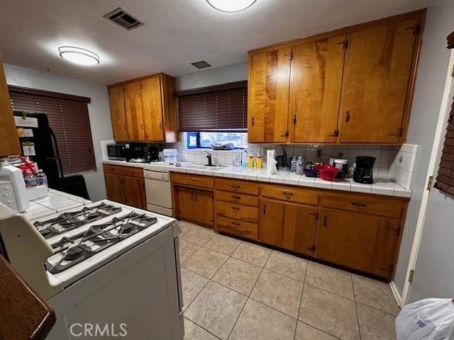 kitchen with tasteful backsplash, sink, tile countertops, and white appliances