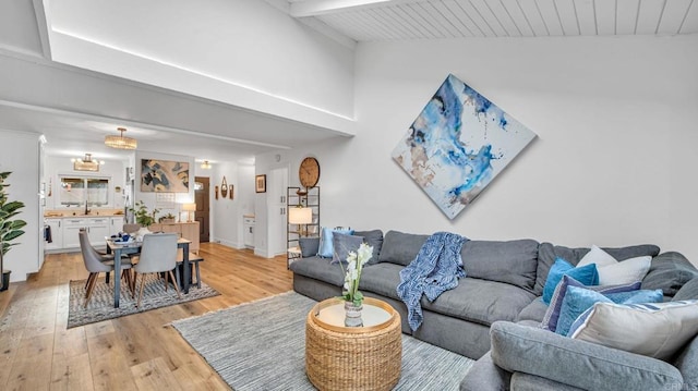 living room with light wood-style floors, beamed ceiling, and high vaulted ceiling