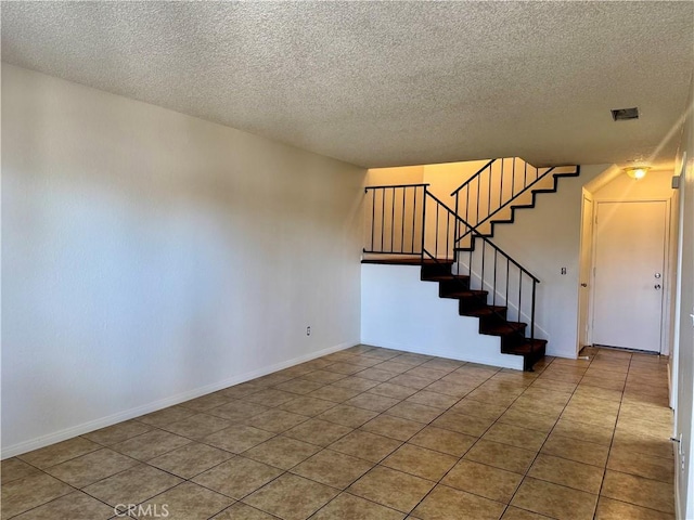 tiled empty room with a textured ceiling