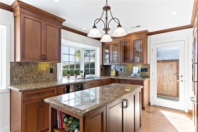 kitchen with black dishwasher, brown cabinets, a sink, and a center island