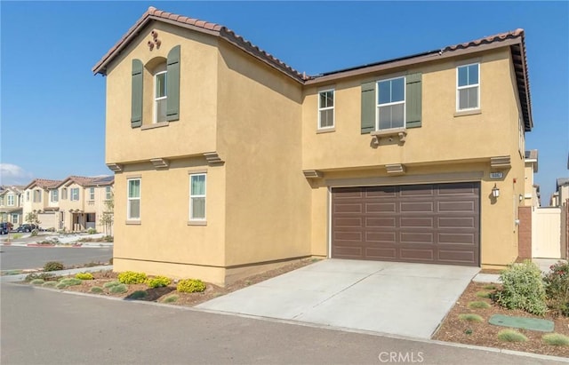 view of front of property with stucco siding, an attached garage, a residential view, driveway, and a tiled roof