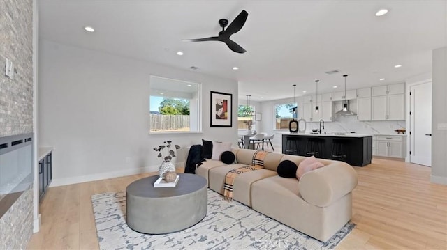 living room featuring sink, light hardwood / wood-style floors, and ceiling fan