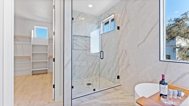 bathroom with hardwood / wood-style flooring, shower with separate bathtub, and tile walls