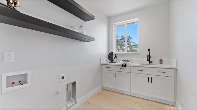 clothes washing area featuring sink, cabinets, light wood-type flooring, hookup for a washing machine, and hookup for an electric dryer