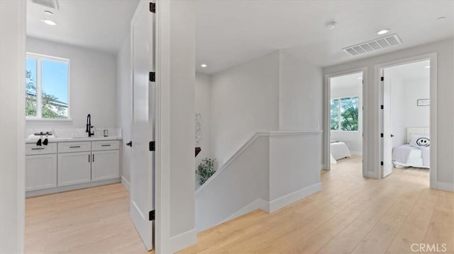 corridor with sink and light hardwood / wood-style floors