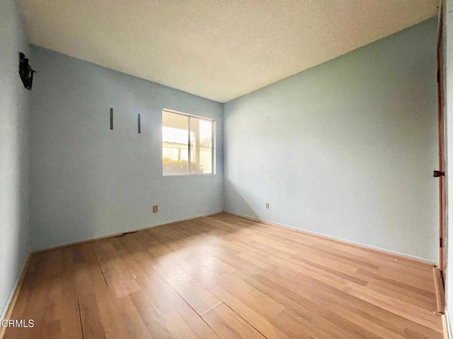 unfurnished room featuring a textured ceiling and light wood-type flooring