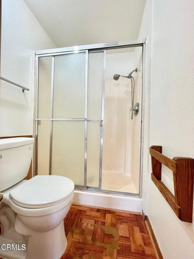 bathroom featuring toilet and a shower with door