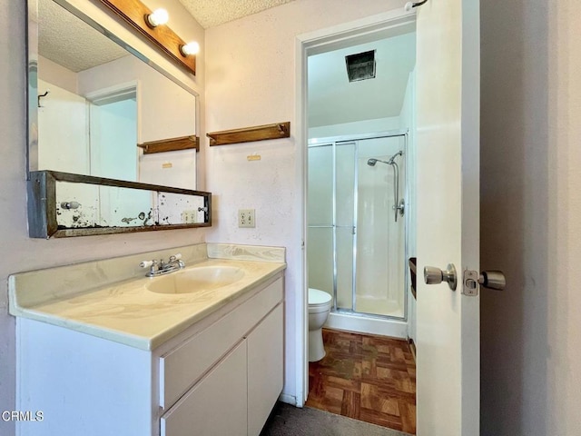 bathroom featuring parquet floors, vanity, toilet, and a shower with door